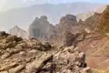 Felsige Berglandschaft mit unterschiedlichen Gesteinsformationen und Bergketten im Hintergrund.