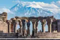 Blick auf die Säulen und Bögen der Ruinen von Zvartnots mit dem Berg Ararat im Hintergrund.