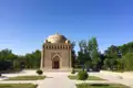 Historisches Mausoleum mit Kuppel und kunstvollen Verzierungen, umgeben von Bäumen und Wegen.