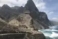 Wanderer auf einem Küstenpfad mit Blick auf die raue Landschaft und das Meer.