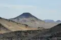 Kegelförmiger Berg in einer wüstenartigen Landschaft, aufgenommen während der Reise.