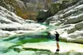 Eine Person betrachtet das türkisfarbene Wasser und die weißen Felsen der Schlucht.
