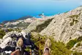 Blick von den Wanderschuhen eines Wanderers auf die Küste und eine Stadt von einem Berggipfel aus.