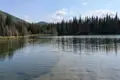 Ein klarer Bergsee mit Spiegelungen der umliegenden Nadelbäume und Berge.