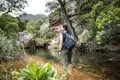 Wanderin genießt eine Pause am Ufer eines Bachs während ihrer Wanderung.