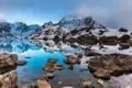 Ruhiger Bergsee mit Spiegelung der umliegenden schneebedeckten Berglandschaft.