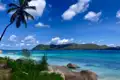 Türkisfarbenes Wasser, Palmen und eine Insel im Hintergrund.