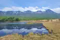 Stille Landschaft mit einem See, der die schneebedeckten Berge und den bewaldeten Uferbereich spiegelt.