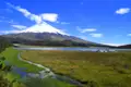 Der Cotopaxi Vulkan, der höchste aktive Vulkan Ecuadors, dominiert die Landschaft.  Im Vordergrund befindet sich ein See und Feuchtgebiete.