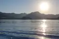 Sonnenuntergang über dem Meer mit Bergen und Küstenlinie im Hintergrund.