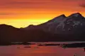Sonnenuntergang über schneebedeckten Bergen und eisbedecktem Wasser.