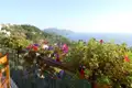 Balkon mit Blumen und Blick auf das Meer und die Hügel.