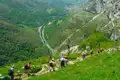 Wandergruppe auf einem Bergpfad mit Blick auf das Flusstal und die umliegende Landschaft.