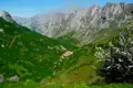 Blick auf ein Bergdorf inmitten eines grünen Tals, umgeben von hohen Bergen.