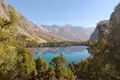 Ein klarer Bergsee, umgeben von Bäumen und Bergen.