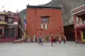 Kinder spielen Fußball vor einem roten Gebäude, das Teil einer kulturellen Stätte sein könnte.