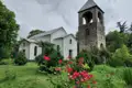 Historische Kirche mit separatem Glockenturm und blühendem Rosengarten.
