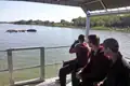 Reisende beobachten Flusspferde mit einem Fernglas vom Boot aus.