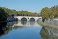 Historische Brücke über den Tiber in Rom mit dem Petersdom im Hintergrund.
