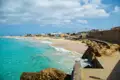 Küstenlandschaft mit türkisfarbenem Wasser und Sandstrand.
