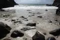 Strand mit Steinen und Wellen