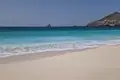 Türkisblaues Wasser und weißer Sandstrand an einem Reiseziel.