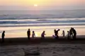 Sonnenuntergang am Strand mit spielenden Menschen.