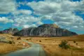 Eine Straße führt durch eine savannenartige Landschaft zu imposanten Felsformationen.