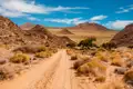 Unbefestigte Straße in einer trockenen, bergigen Landschaft.