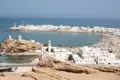 Panoramablick auf eine Küstenstadt mit weißer Architektur, einer Moschee und Booten in der Bucht.