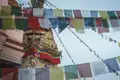 Nahaufnahme einer Stupa mit bunten Gebetsfahnen, die im Wind wehen.