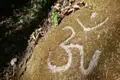 Om-Symbol auf einem bemoosten Felsen.