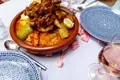 Couscous mit Fleisch, Gemüse und Eiern in einer Terrakotta-Schale.