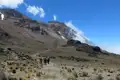 Wanderer auf einem Bergpfad in Richtung eines schneebedeckten Gipfels.