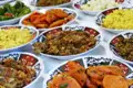 Eine Auswahl an marokkanischen Speisen, darunter gekochte Karotten, grüne Paprika, Reisgerichte und verschiedene Fleisch- oder Gemüse-Eintöpfe.