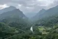 Panoramablick auf ein Flusstal inmitten bewaldeter Berge.