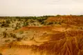 Erodierte Sanddünenlandschaft mit spärlicher Vegetation.