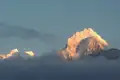 Schneebedeckte Berggipfel, die durch die Wolken scheinen.