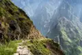 Wanderer auf einem Bergpfad mit Blick auf eine Schlucht.