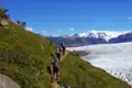 Wanderer auf einem Bergpfad mit Blick auf einen Gletscher in den Bergen.
