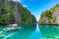 Traditionelles Auslegerboot in einer Bucht der Philippinen, umgeben von Kalksteinfelsen und türkisfarbenem Wasser.