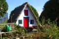 Traditionelles Haus mit Strohdach und buntem Anstrich in einem Garten.