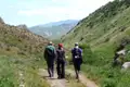 Drei Wanderer mit Rucksäcken auf einem Bergpfad.