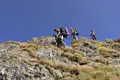 Wanderer beim Aufstieg auf einem Bergkamm mit Stahlseilsicherung.