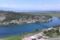 Luftbild eines Dorfes an einem Fluss mit Brücke und See im Hintergrund.