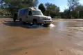 Safari-Fahrzeug durchquert ein Gewässer, Hinweis auf mögliche Flussdurchquerungen oder Fahrten durch überflutete Gebiete während der Safari.