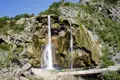 Szenerischer Wasserfall mit einem Holzsteg im Vordergrund.