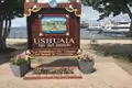 Willkommensschild in Ushuaia, Argentinien, mit dem Schriftzug 'Ende der Welt' und Blick auf den Hafen.
