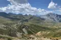 Grüne Berghänge und Gipfel unter einem bewölkten Himmel.