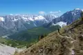 Wanderer auf einem Bergpfad inmitten einer beeindruckenden Bergkulisse mit schneebedeckten Gipfeln.